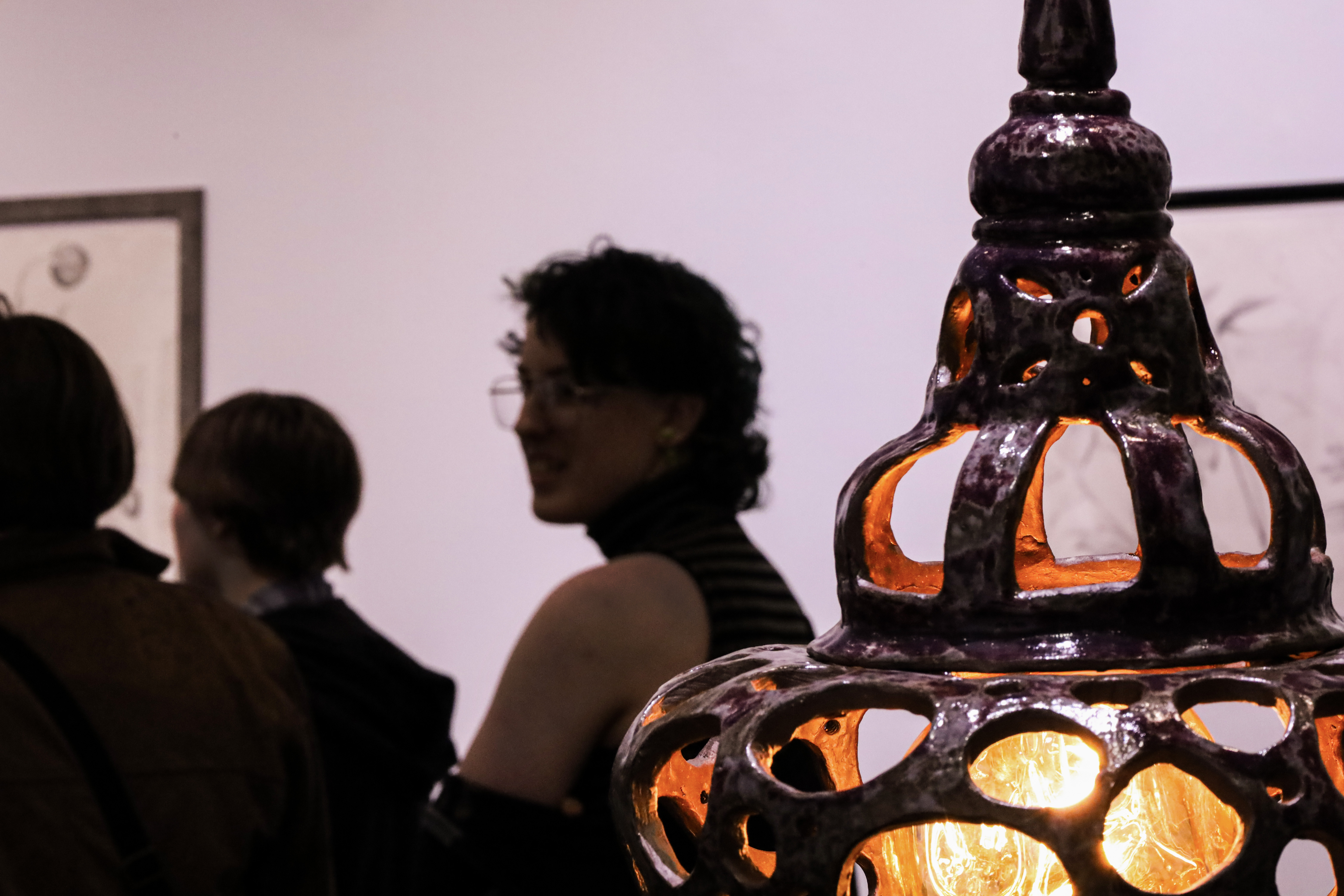 A lamp glows in the corner, silhouetting three people in the background